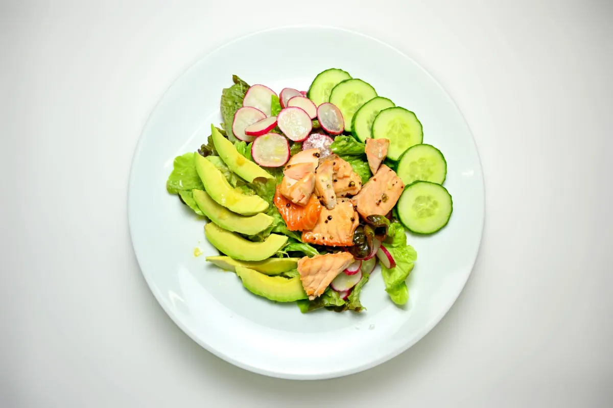 Colorful keto meals for beginners with salmon, avocado, eggs and fresh greens on table