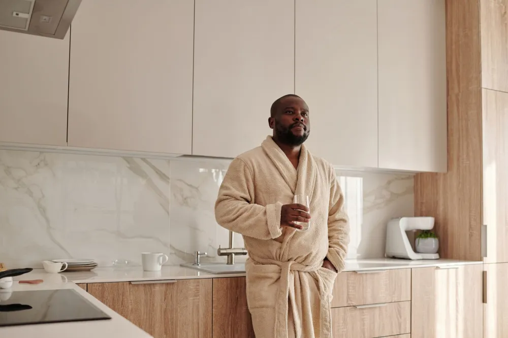 Man drinking a glass of water in his kitchen during early ketosis