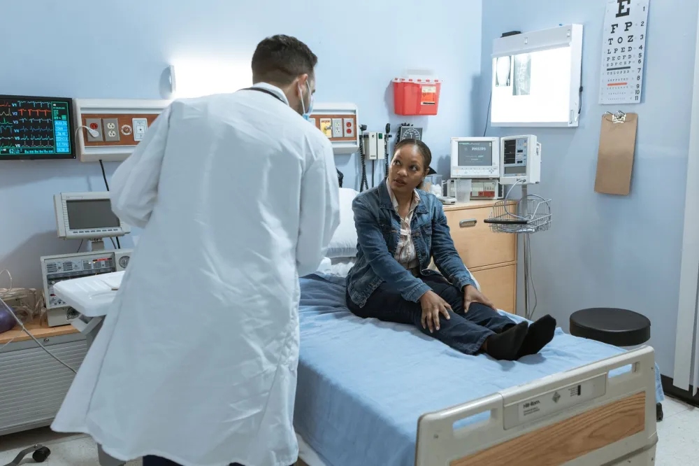Doctor pressing on a patient's lower leg to check swollen legs for pitting