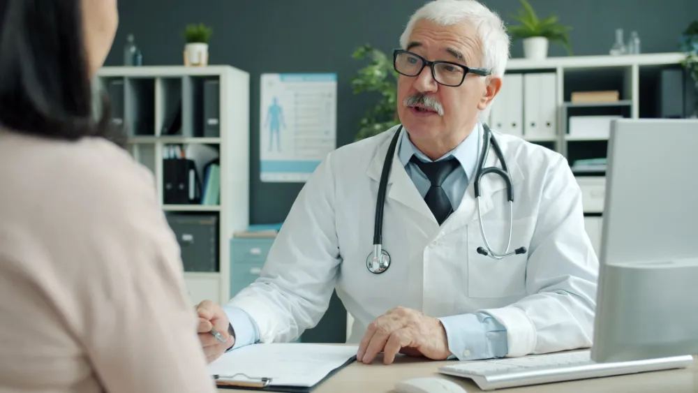 Lower Abdominal Pain in Women: 10 Causes and Warning Signs 3 Female patient describing her pelvic pain symptoms to a doctor in a bright clinic