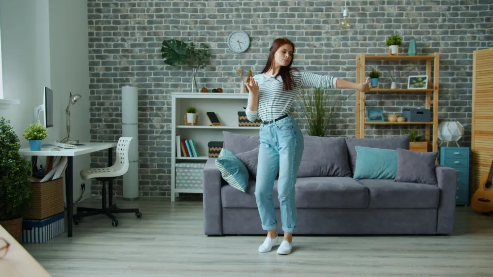 Person applying a heating pad to their lower back while resting on a sofa
