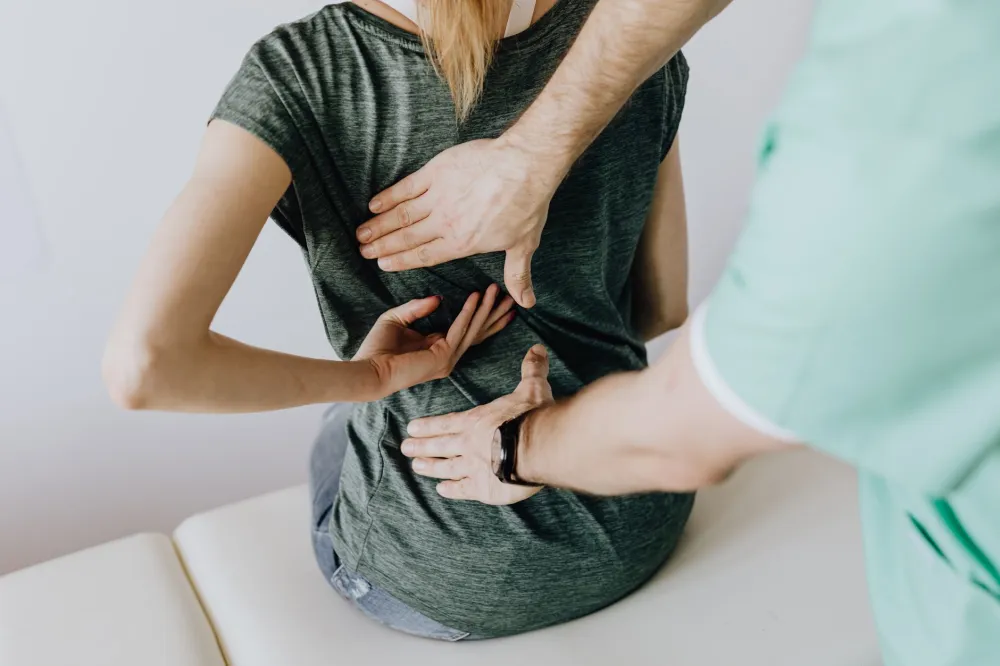 Pain Between the Shoulder Blades: Causes and Relief 4 Physical therapist working on a patient's upper back and shoulder blade area