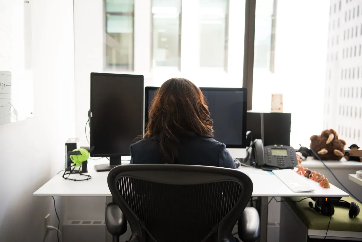 Woman holding upper back with pain between the shoulder blades at a desk