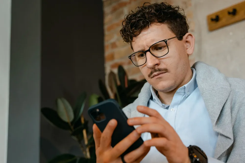 Man checking his phone at home to learn what causes a pimple on foreskin skin