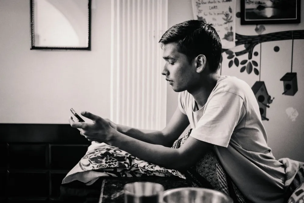 Teenager scrolling through social media on a phone in bedroom