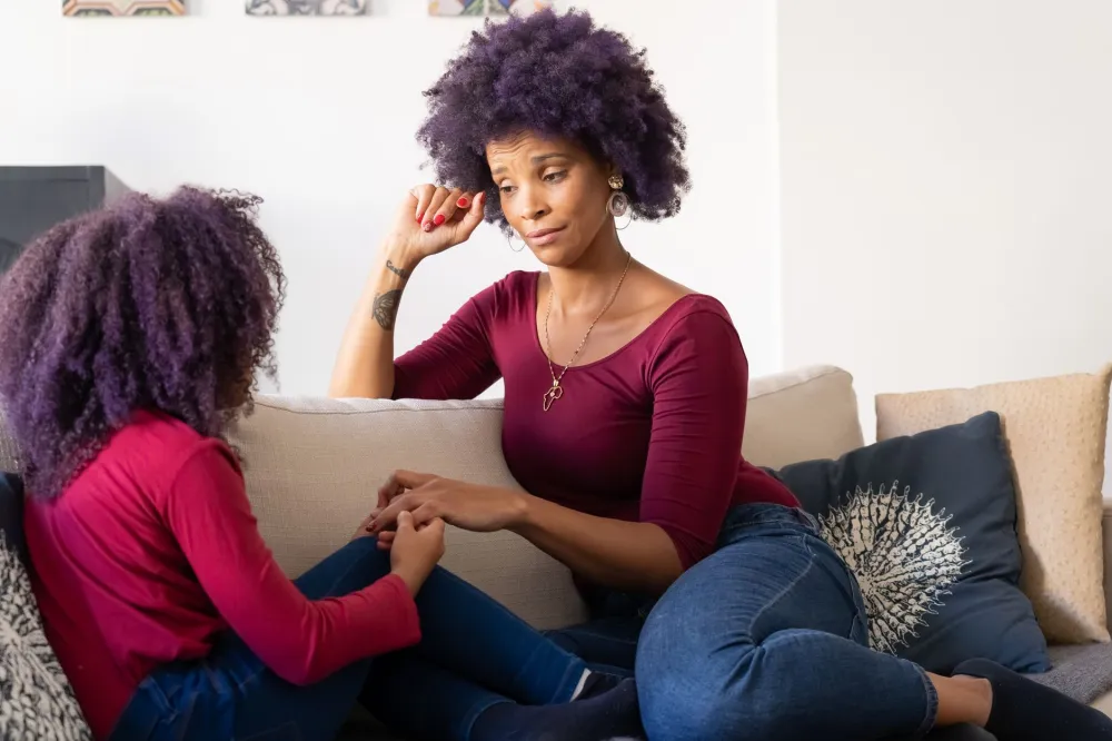 Parent and child having a calm conversation on a living room couch
