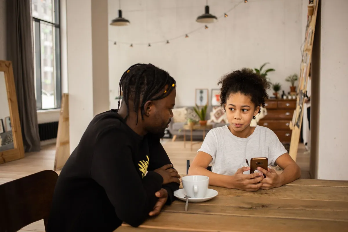 Young child using a smartphone at a kitchen table with food nearby