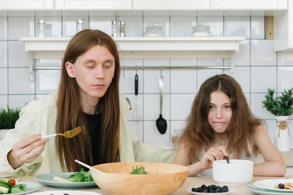 Parent and child eating a colorful healthy meal together at the kitchen table
