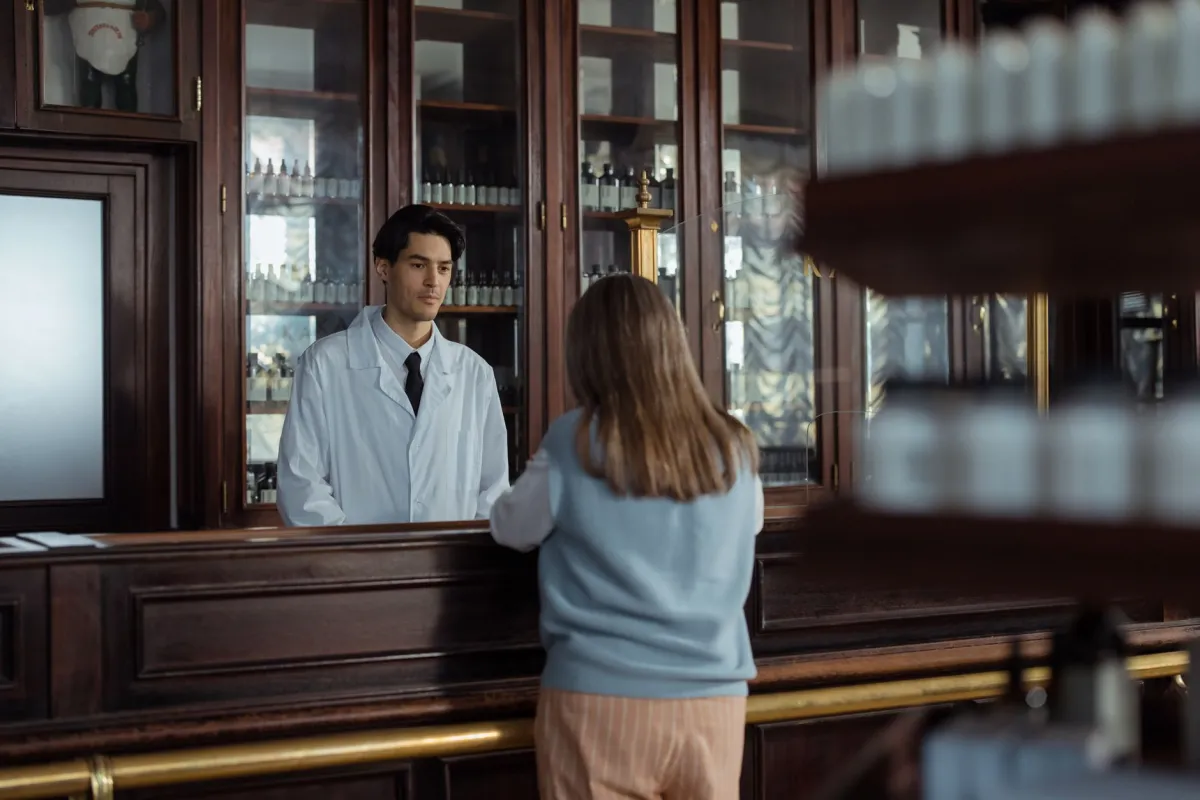 Pharmacist handing a prescription bag to a customer discussing Wegovy cost and savings